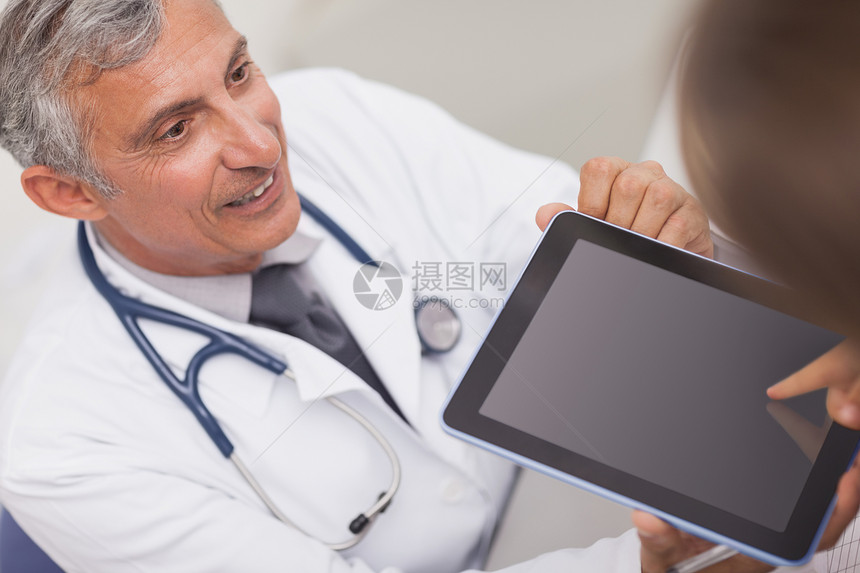 医生一边看病人一边拿着平板电脑 一边看病人图片
