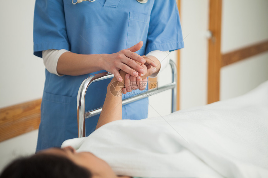 病人躺在医疗床上 抱着一名护士的手图片