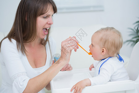 母亲在张开嘴时喂养婴儿背景图片