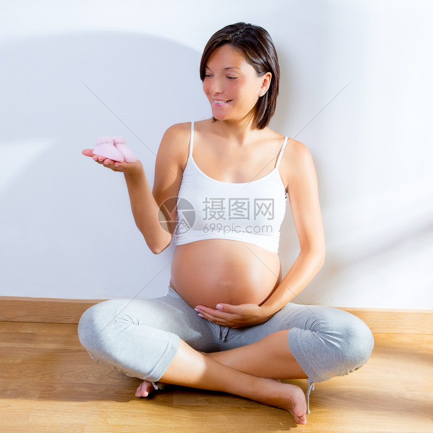 手握着婴儿鞋的美丽的怀孕妇女妈妈分娩父母女孩女儿家庭身体女性女士母亲图片