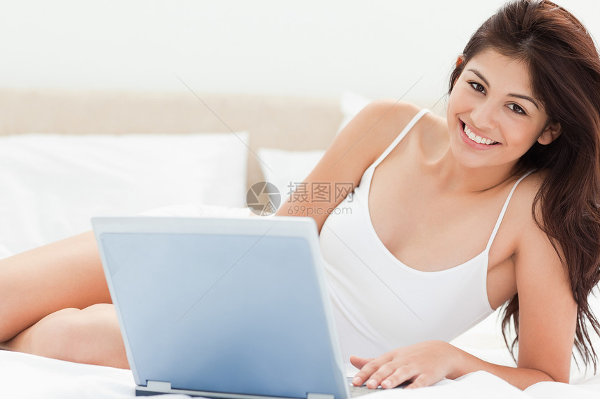 女人在她用笔记本电脑的时候 仰望和微笑着向前看图片