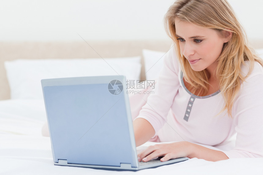 女人躺在床上 同时用笔记本电脑图片