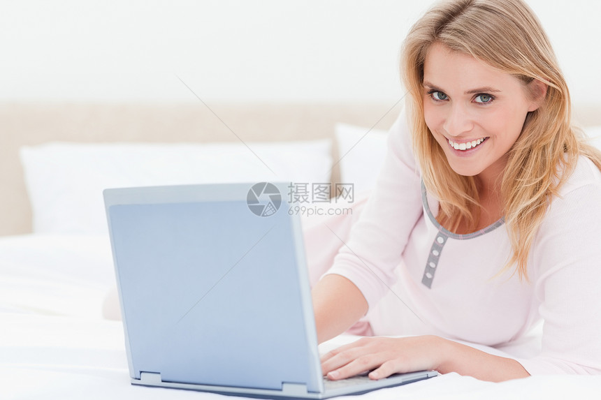 女人躺在床上 用笔记本电脑 向前看微笑图片