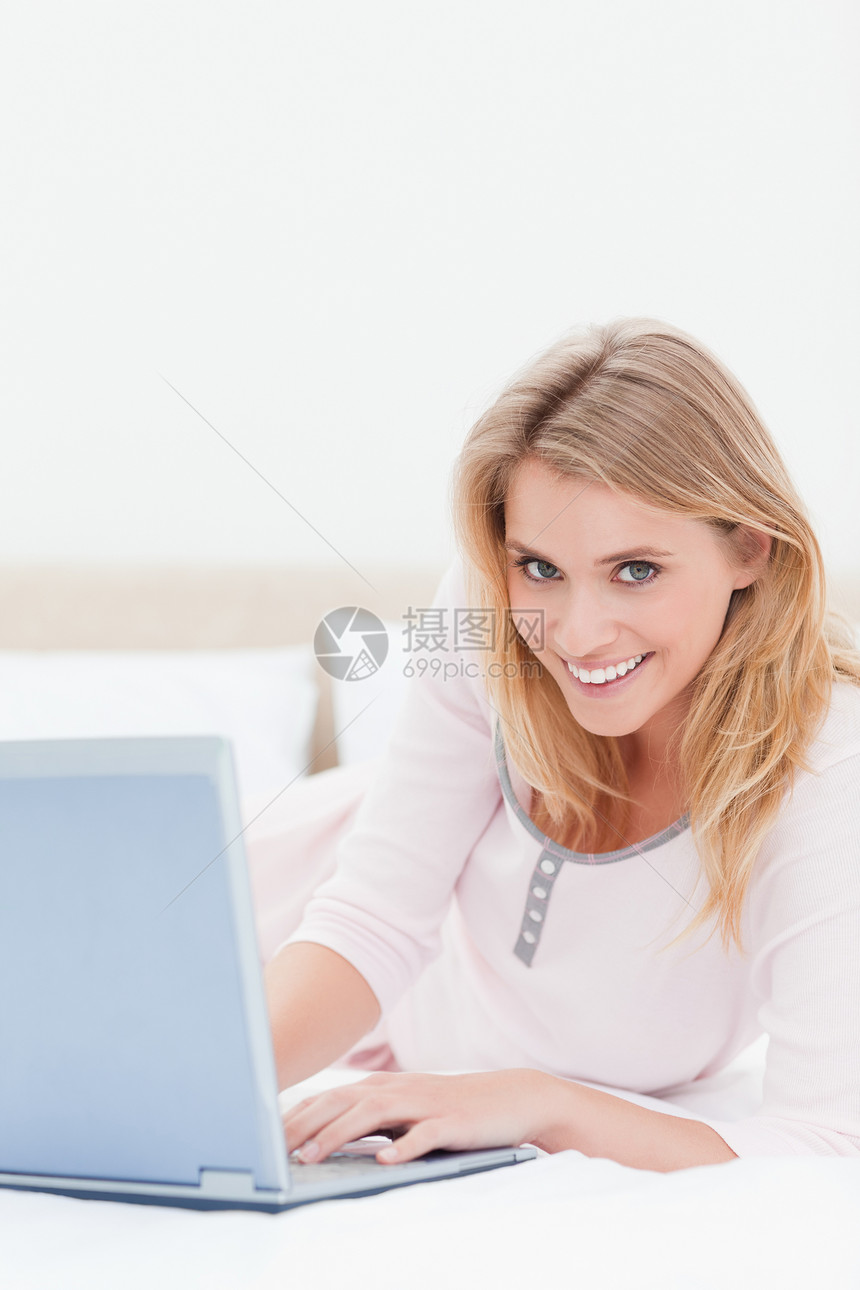 女人躺在床上 拿着笔记本电脑 一边向前看图片