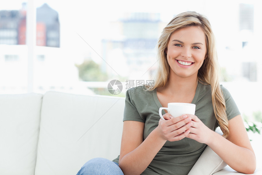 女人笑着 手拿着杯子坐在沙发上图片