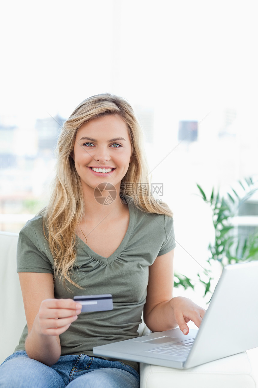 女人用信用卡和笔记本电脑在沙发上使用图片