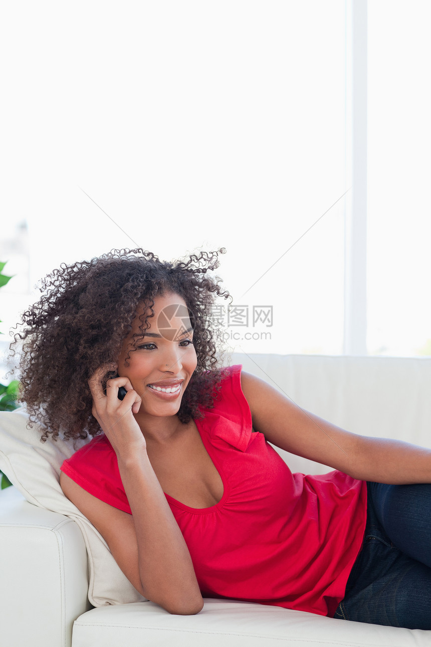 女人在沙发上打个电话时笑着微笑图片