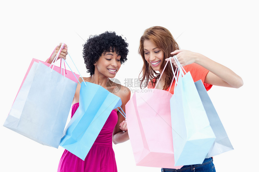青少年女孩互相看对方的买东西消费者混血儿快乐外表女性开支喜悦微笑影棚购物图片