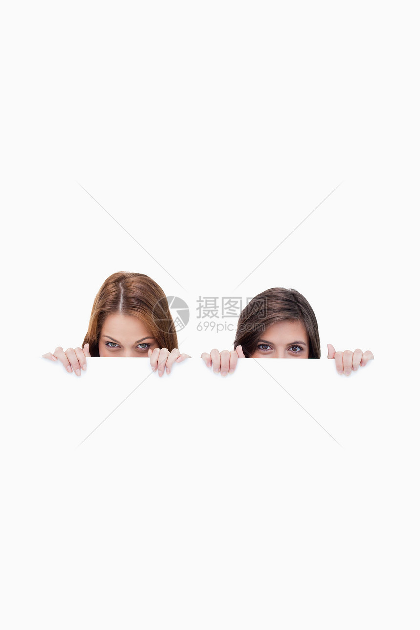 两个朋友秘密躲在一张空白海报后面图片