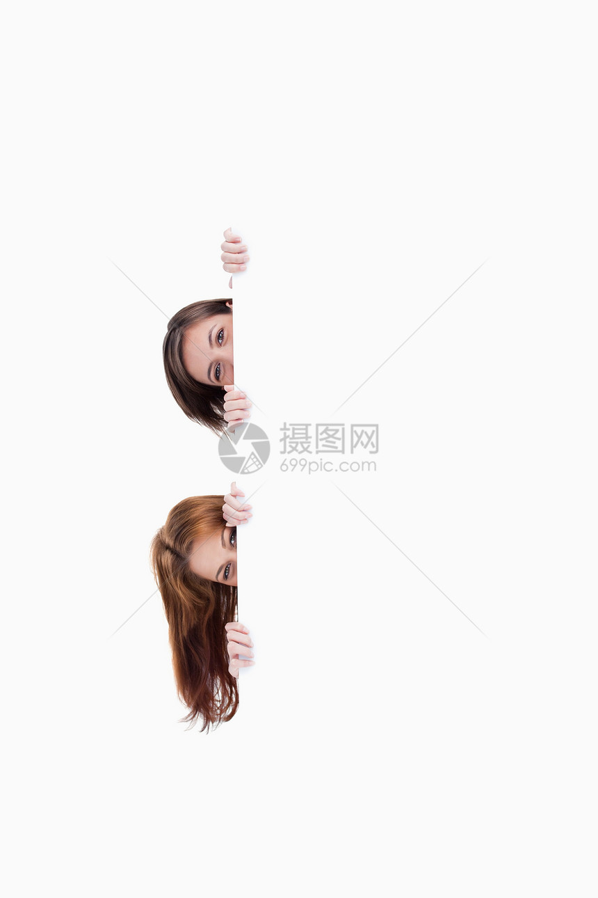两个少女把头从一张空白海报上挖出来图片