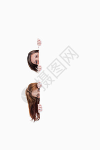 两个少女把头从一张空白海报上挖出来背景图片