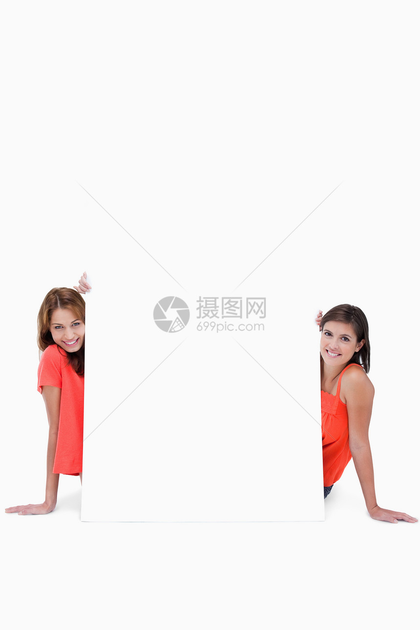 两个笑着笑着的少女坐在一张空白海报后面图片