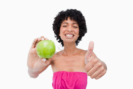 笑笑的少年拿着绿苹果 举起她的拇指高清图片