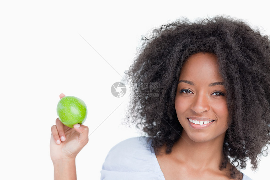 微笑的女人拿着一只绿苹果 在她的手指之间图片