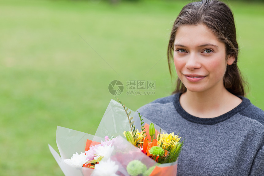 年轻平静的女孩拿着一束鲜花 站在一个P图片