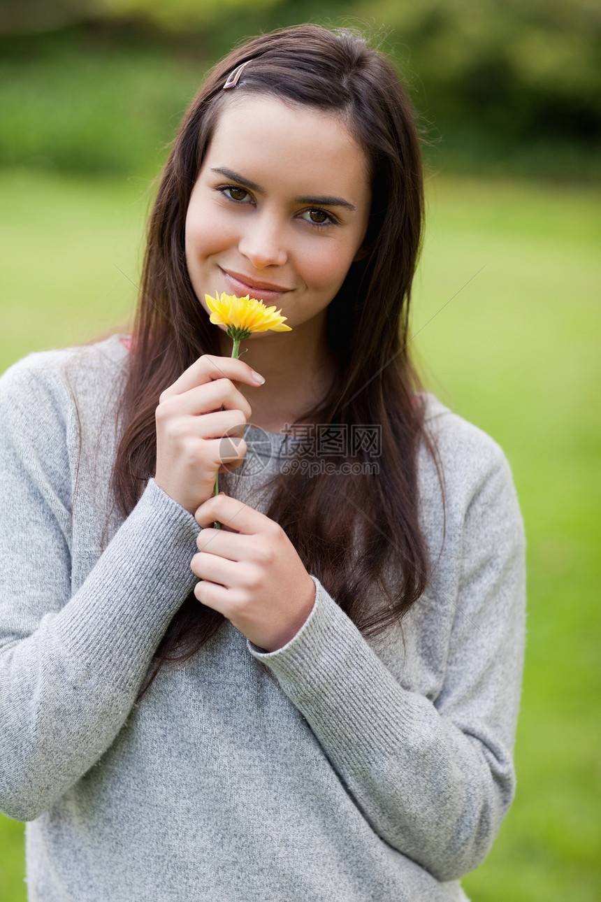 年轻放松的女士 在一旁站着时 闻着黄色花朵的气味图片