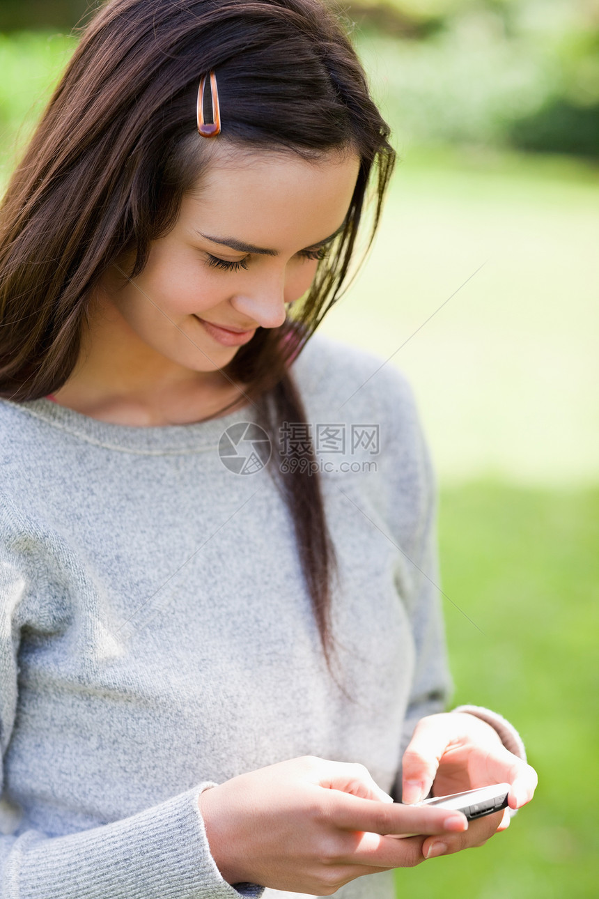 放松的年轻女孩用手机发短信 而Stst图片
