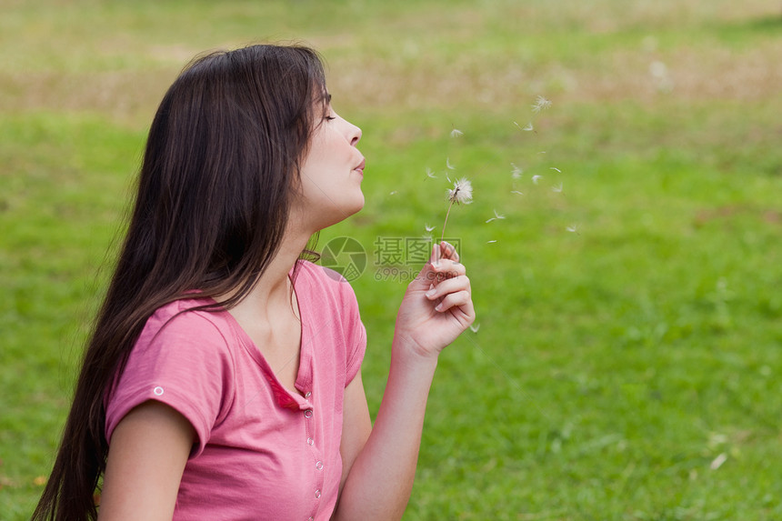 年轻放松的女人吹响花朵图片