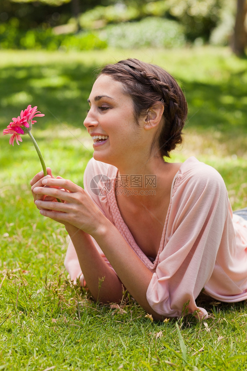 女人躺在她面前笑着看着一朵鲜花图片