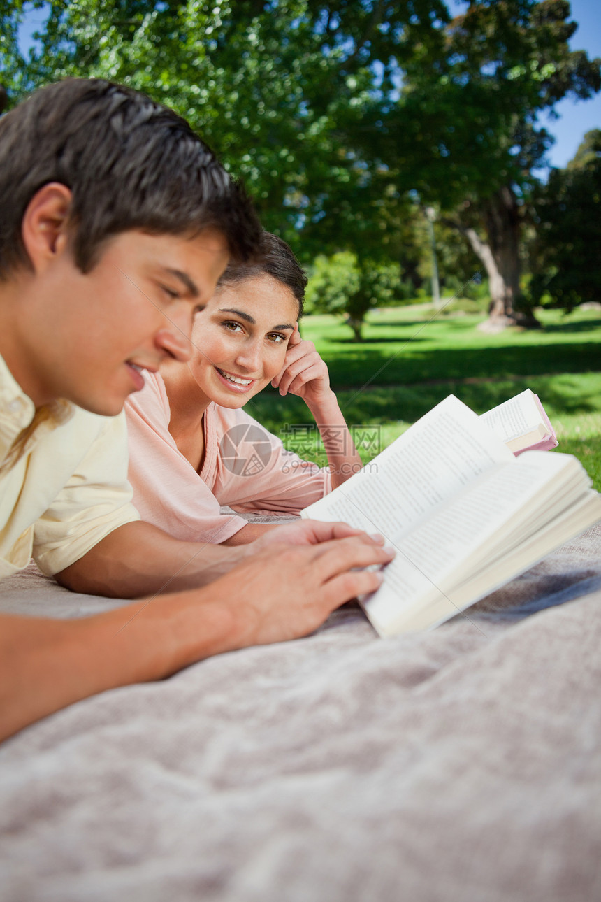 女人在公园里和朋友一起看书时看着身边图片