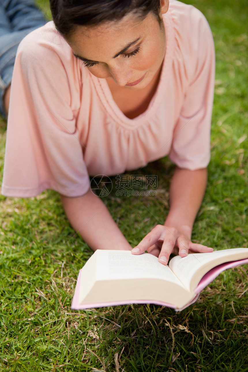 女人躺在草地上看着一本书时图片