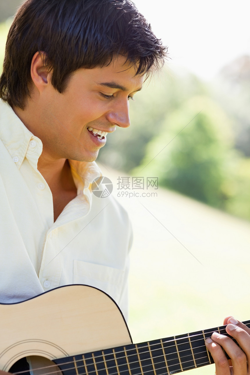 男人在弹吉他时微笑图片