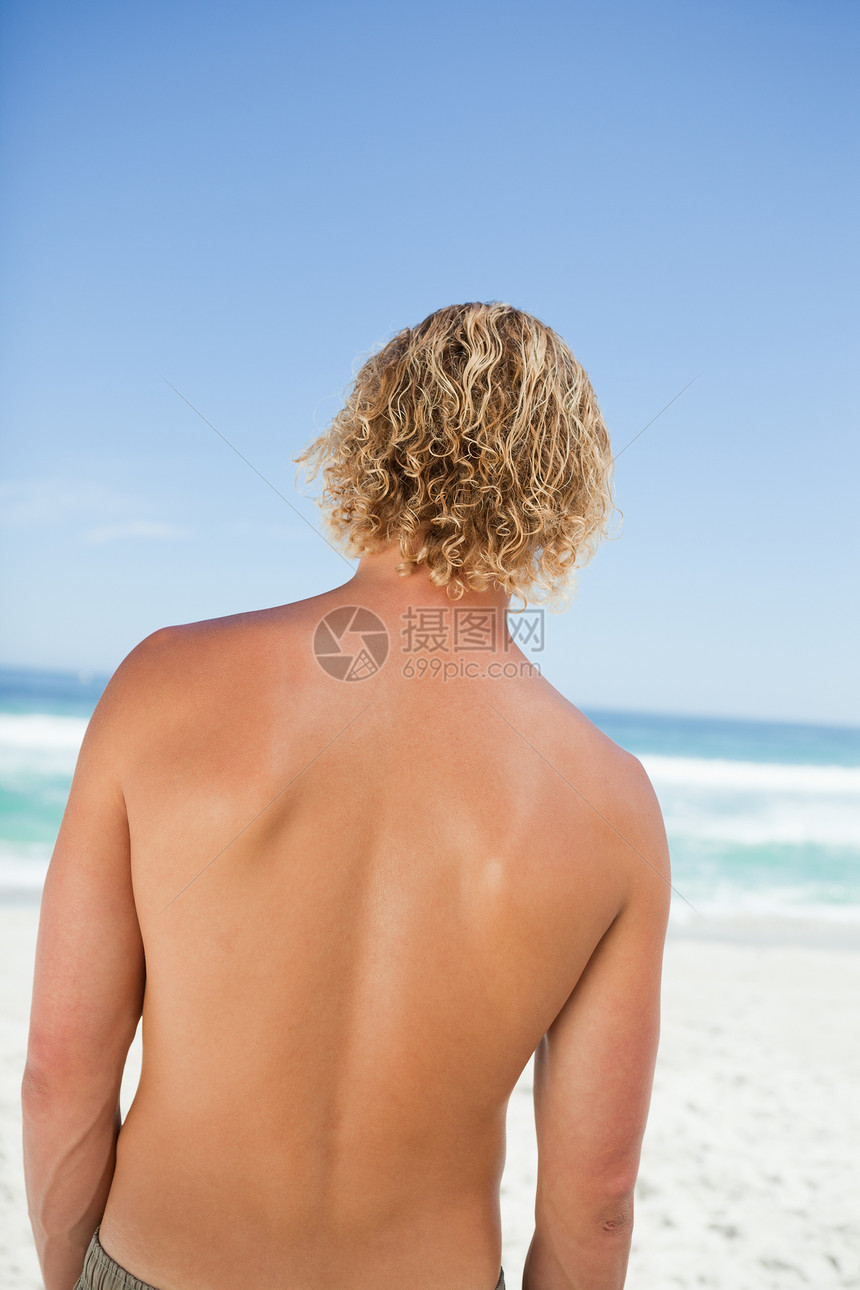看着海洋的金发年轻男人的近视图片
