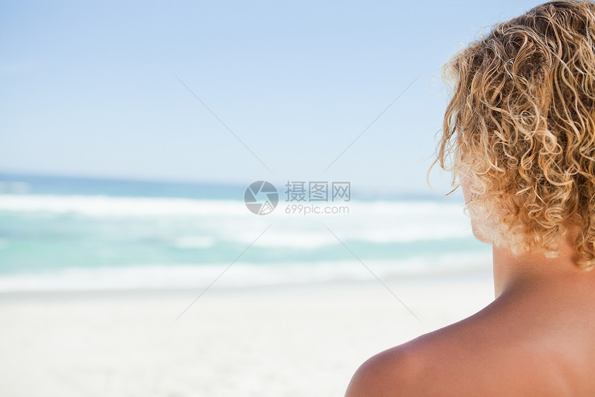年轻金发金发金发男 在晒太阳时看着海图片
