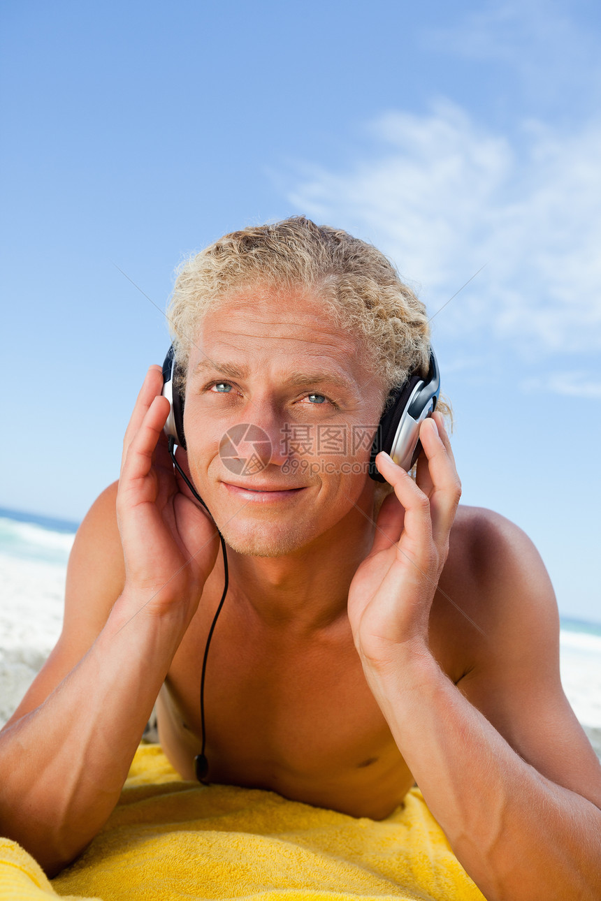 坐在黄色沙滩毛巾上 一边听音乐边笑着的年轻人图片