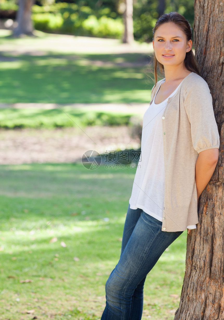 在公园里的女人靠在树上图片