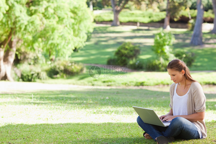 坐在草坪上的女人 在笔记本上工作图片