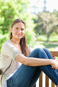 微笑的女人在公园长椅上享受阳光背景图片