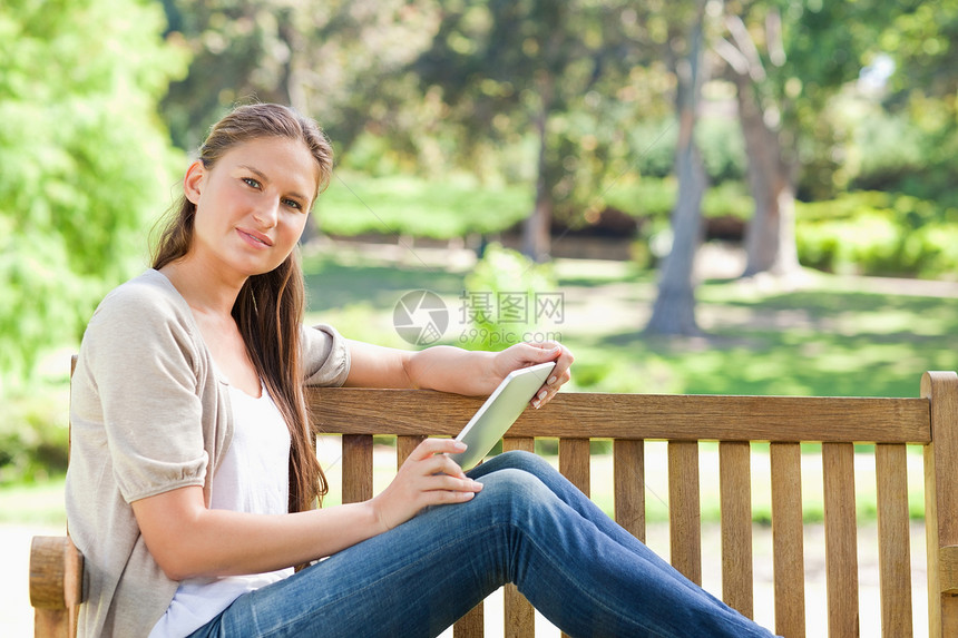 公园长椅上有平板电脑的女人的侧视角图片