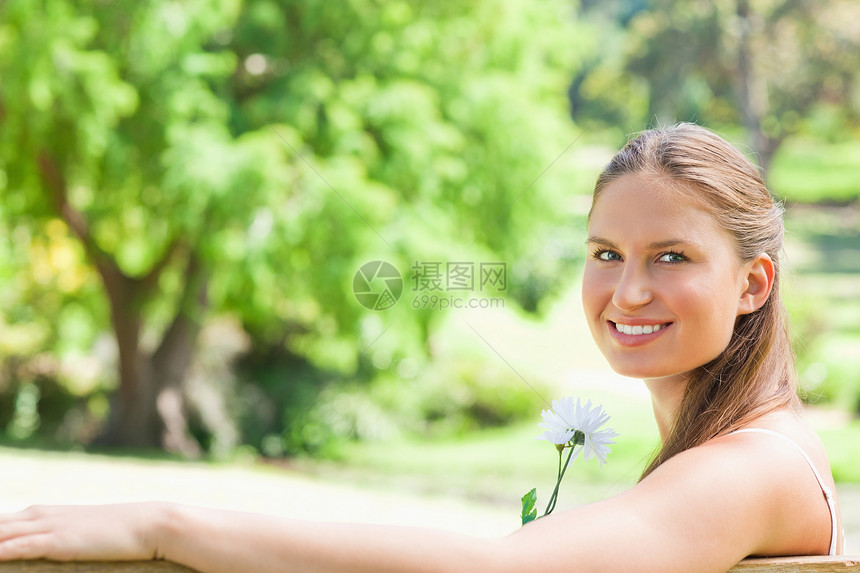 一个带着花朵微笑的女人的侧面景色图片