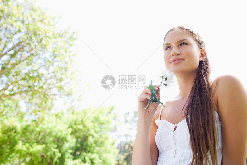 有花的女人在公园里享受着白天的花朵图片