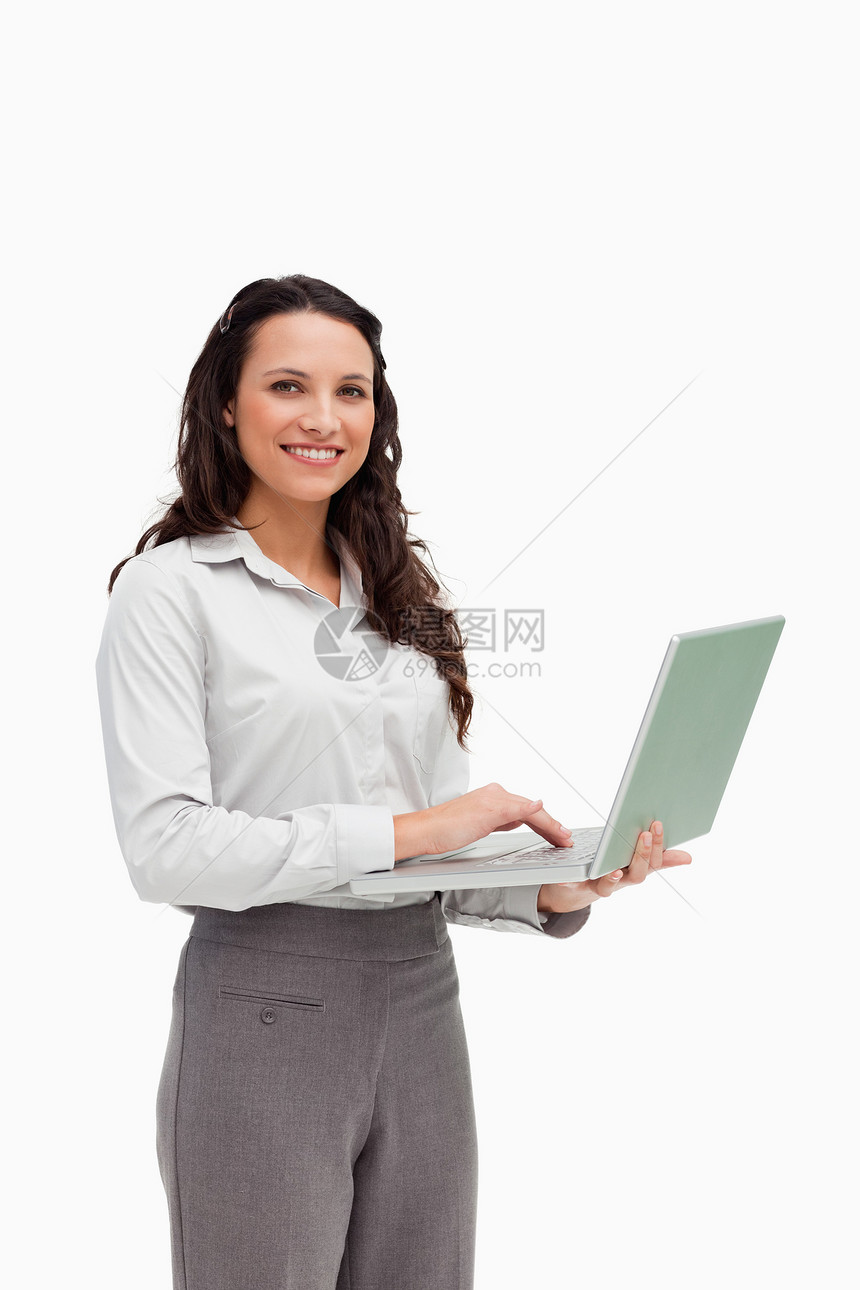使用笔记本电脑时站立的褐发美女肖像图片
