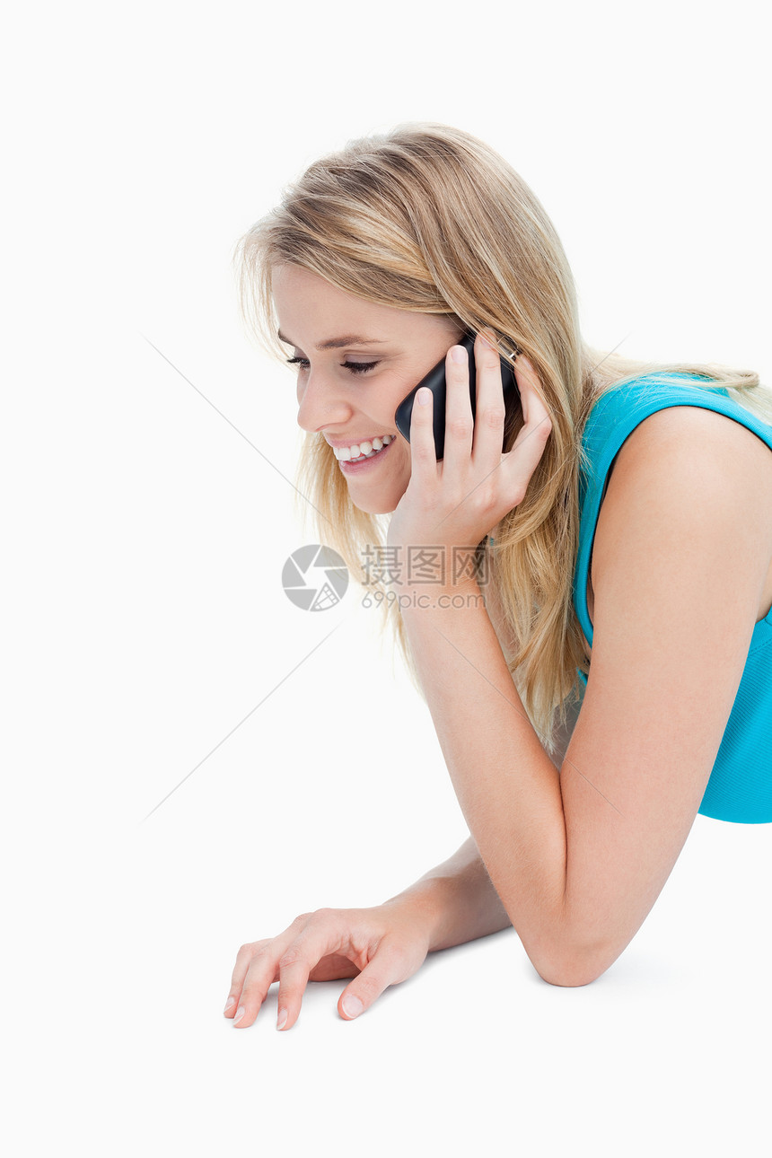 一个微笑着的年轻女人 正在用手机说话金发女郎手臂说谎快乐休息外表影棚呼唤头肩听力图片