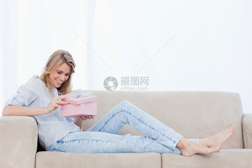 一个快乐的女人在粉红盒里看着礼物图片