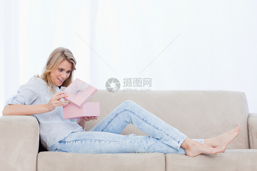 一个惊讶的女人在粉红色盒子里 看着礼物图片
