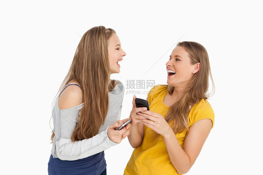 两名年轻女子在拿着手机时笑着笑图片