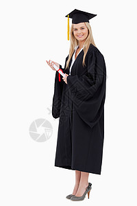 身着毕业长袍的金发女学生 持有文凭背景图片