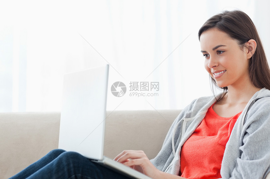 一个女人躺在沙发上 用笔记本电脑微笑图片