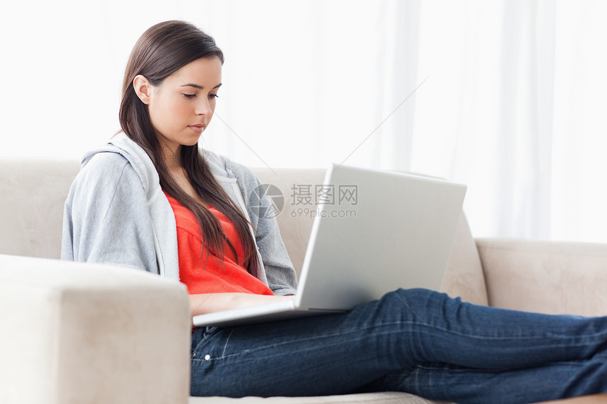 一个女人带着笔记本电脑在沙发上 双腿伸展图片