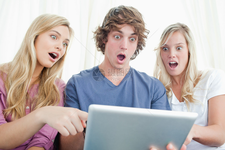 三个震惊的朋友在看平板电脑的屏幕上图片