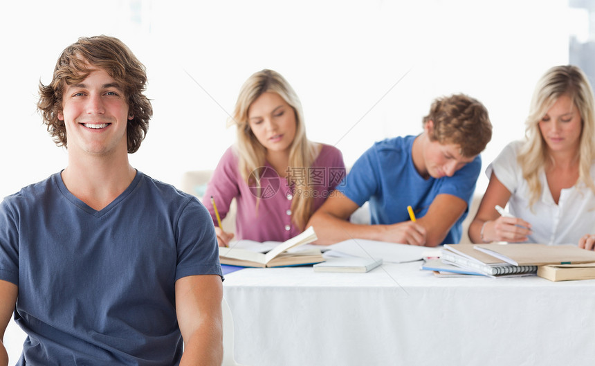 一个年轻男人坐在他工作班同学面前的年轻人图片