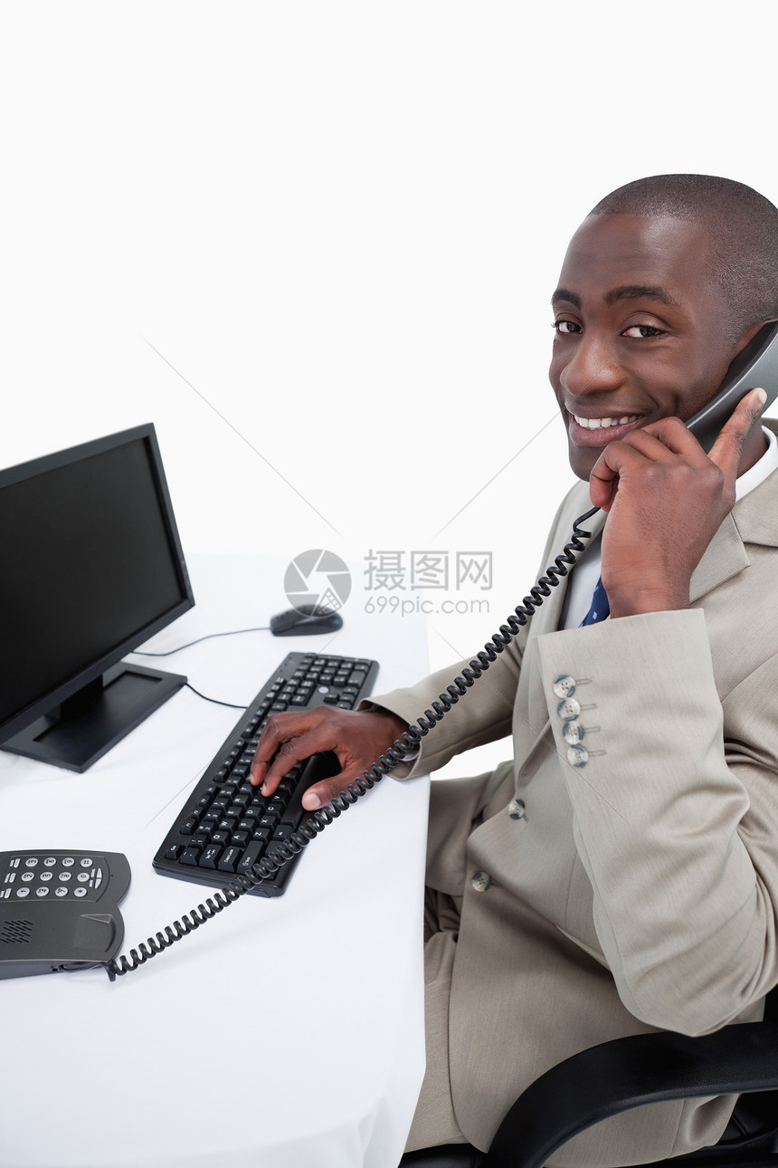 一位男性秘书的侧边视图 他用手机接通了电话桌子老板男人商业微笑人士监视器电脑咨询听筒图片