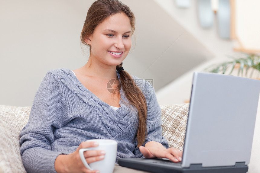 女人在喝茶时用笔记本电脑图片