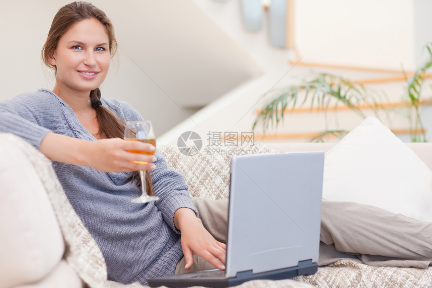 女人在用笔记本电脑时喝酒图片