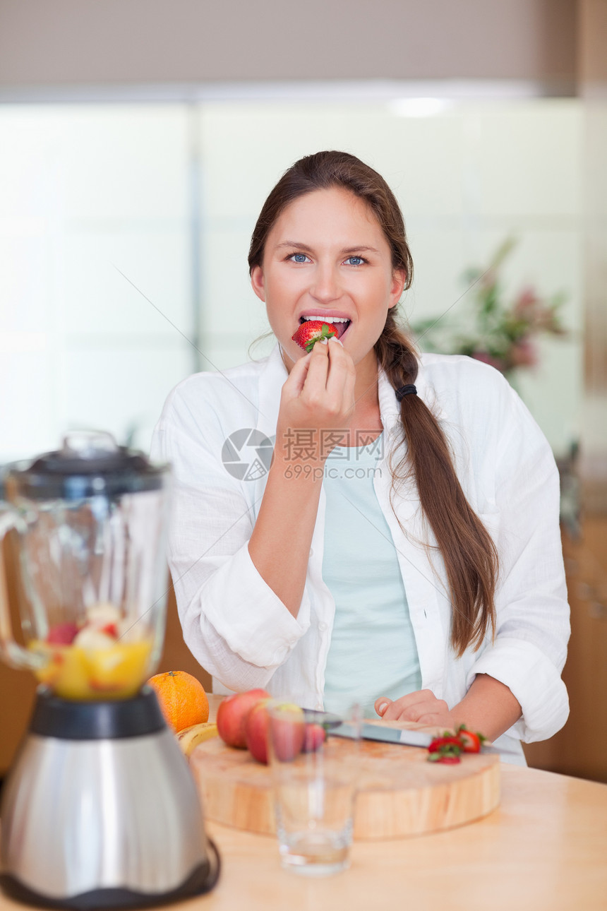 一个女人吃草莓的肖像营养饮食饮料桌子混合器木板厨房冰沙午餐榨汁机图片
