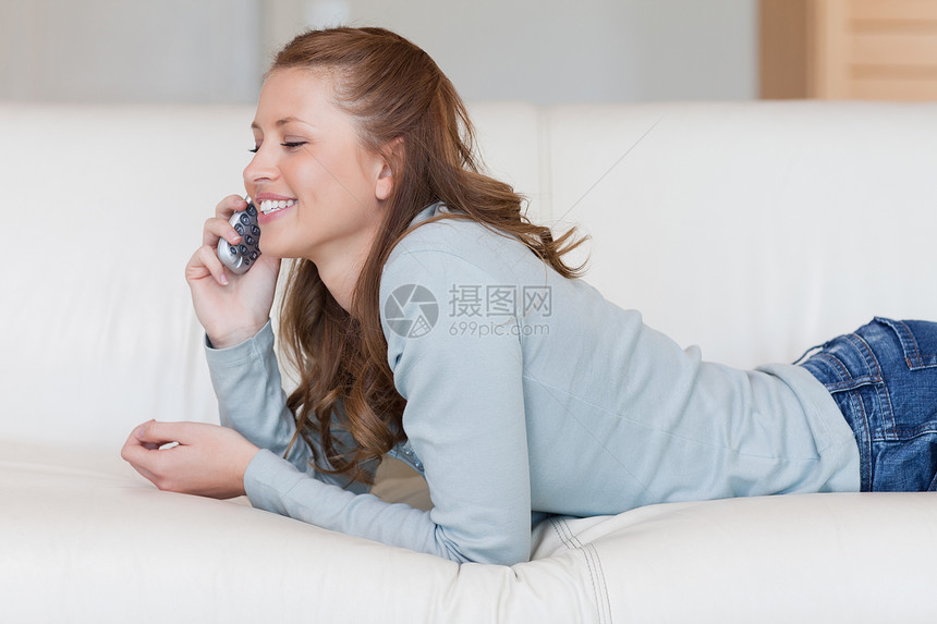 睡沙发上的女人在电话上聊天很愉快图片